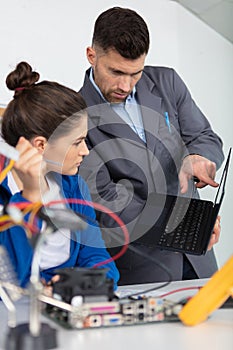 female apprentice repairing computer with help teacher