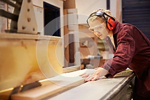 Female Apprentice Using Circular Saw In Carpentry Workshop