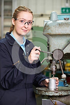 Female Apprentice Using Drill In Factory