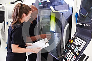 Female Apprentice Working With Engineer On CNC Machinery