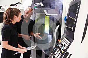 Female Apprentice Working With Engineer On CNC Machinery