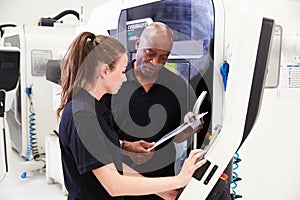 Female Apprentice Working With Engineer On CNC Machinery