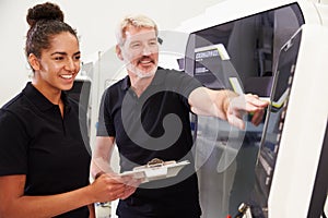 Female Apprentice Working With Engineer On CNC Machinery