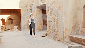 Female archeologist walking among ancient building