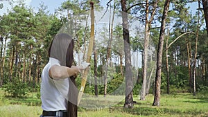 Female archer draving arrow and shooting target