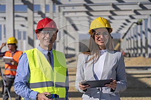 Female Architect With Digital Tablet Standing Next To Construction Supervisor At Construction Site