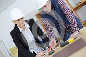 Female architect and foreman examining blueprints in office