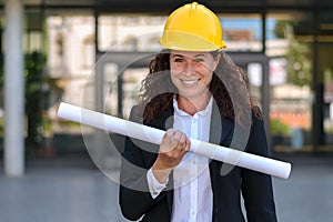 Female architect in a hardhat holding a blueprint