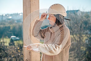 Female architect making notes and remarks during building site inspection