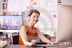 Female Architect In Office Working On Desktop Computer Using Graphics Tablet