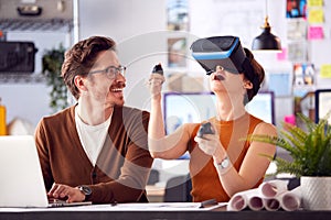 Female Architect Wearing VR Headset In Office Working With Male Colleague At Desk With Laptop