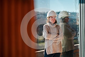 Female architect wearing white hardhat posing on construction site