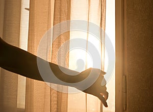 Female arm reaching out to open a curtain