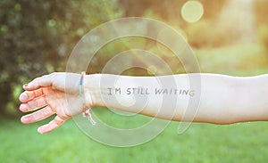 Female arm with text -I'm still waiting- written