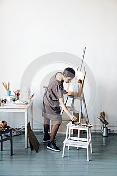 Female artist in her spacious white studio working with watercolor painting