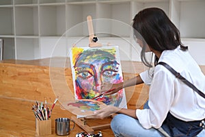 Female Artist painting picture in art workshop.