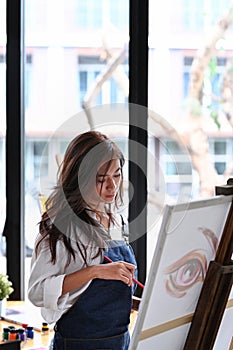 Female artist painting picture on canvas in a creative art studio.