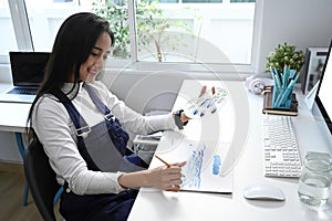 Female artist painting picture on notepad at her workshop.