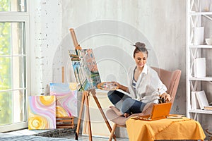 Female artist painting picture in workshop