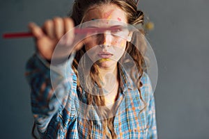 Female artist standing next to the camera with a brush for painting in the studio. A professional female painter draws in a