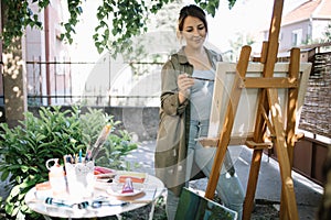 Female artist using paint brush while painting in backyard