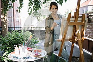 Female artist using paint brush while painting in backyard