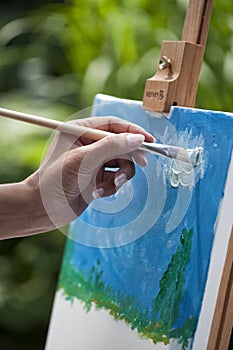 Female artist workes on a painting in a park. Selective focus on