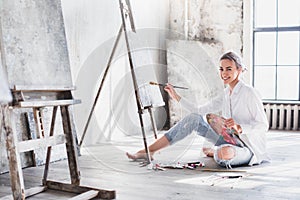 Female artist working on painting In bright daylight studio.