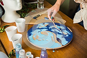 Female artist works on abstract fluid art painting with marble effect