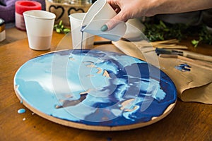 Female artist works on abstract fluid art painting with marble effect