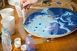 Female artist works on abstract fluid art painting with marble effect