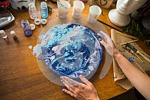 Female artist works on abstract fluid art painting with marble effect