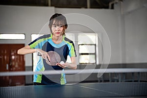 female asian athlete holding ball and paddle preparing to serve