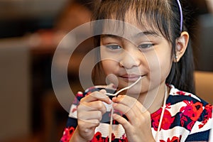 Female asian child while eating noodles. Child eating ramen noodles smiling and enjoying the food. Child eating spaghetti
