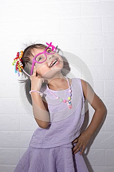 Female asian child girl posing wacky thinking pose while wearing some accessories like crown, necklace and wearing purple dress