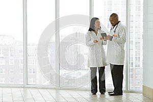 Female Asian doctor with African American doctor with tablet