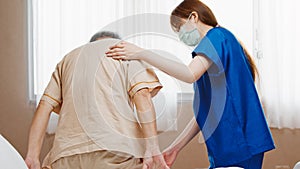 Female Asian nurse wear mask care and check on senior male smile patient in private room in hospital bed. Medical healthcare