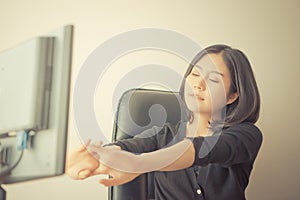 Female Asian office worker stretching out after long hour of work