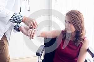 A female Asian patient suffered an accident with her arm broken, causing her to sit in a wheelchair and receiving treatment from a