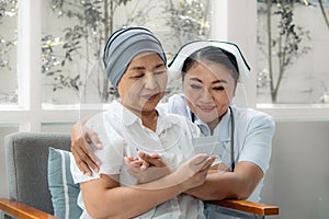 Female Asian senior patient holding health insurance card with asian nurse encourage her to have confident to sickness expense