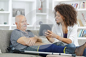 Female assistan showing senior man tablet