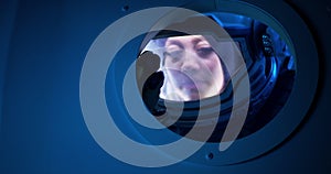 Female astronaut looking out of spaceship porthole