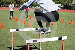 Female athlete bounds over a hurdle