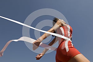 Female Athlete Crossing Finish Line Against Blue Sky photo