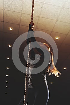 Female athlete doing rope climbing exercise.