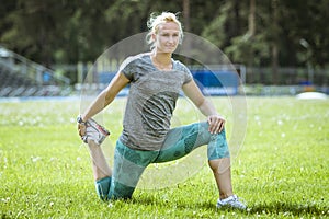female athlete doing stretching on green field
