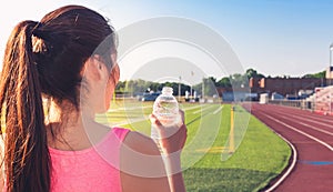 Female athlete drinking water on a running track