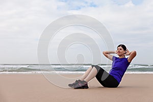 Female athlete executing situps at the beach photo