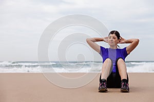 Female athlete executing situps at the beach photo