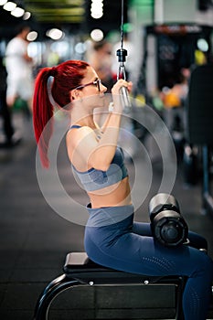 Female athlete exercising in the gym. Fitness woman using gym machines for training